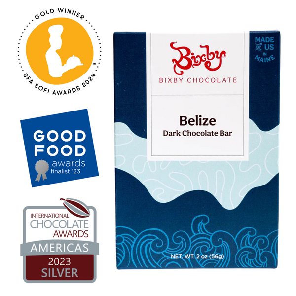 A Bixby Chocolates Organic Belize 70% Dark Chocolate Bar, made with ethically sourced Belizean cacao, is shown in blue ocean-wave packaging with these award badges: Sofi Awards 2024 Gold, Good Food Awards Finalist 2023, and International Chocolate Awards Silver 2023.