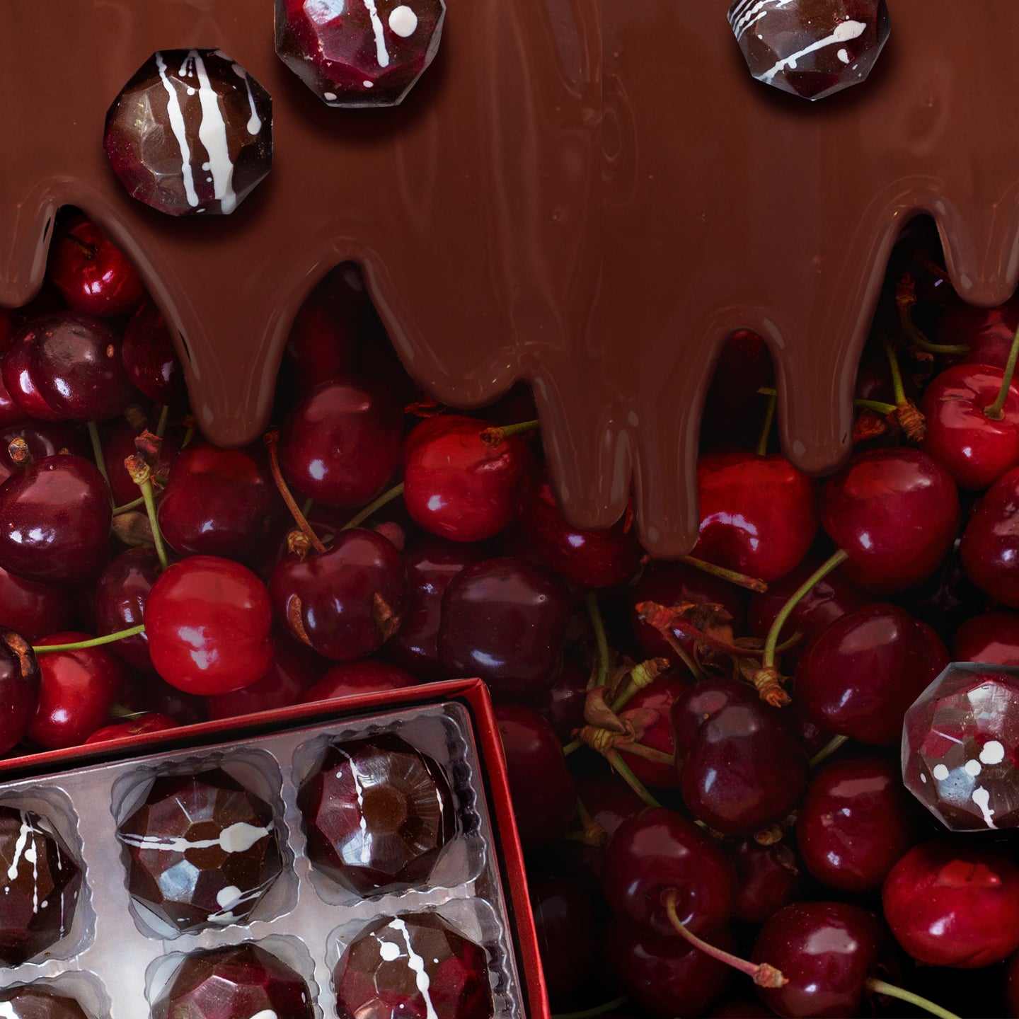 A cluster of fresh red cherries is topped with dripping melted chocolate, while geometric-shaped chocolate candies rest above and in a box at the corner.