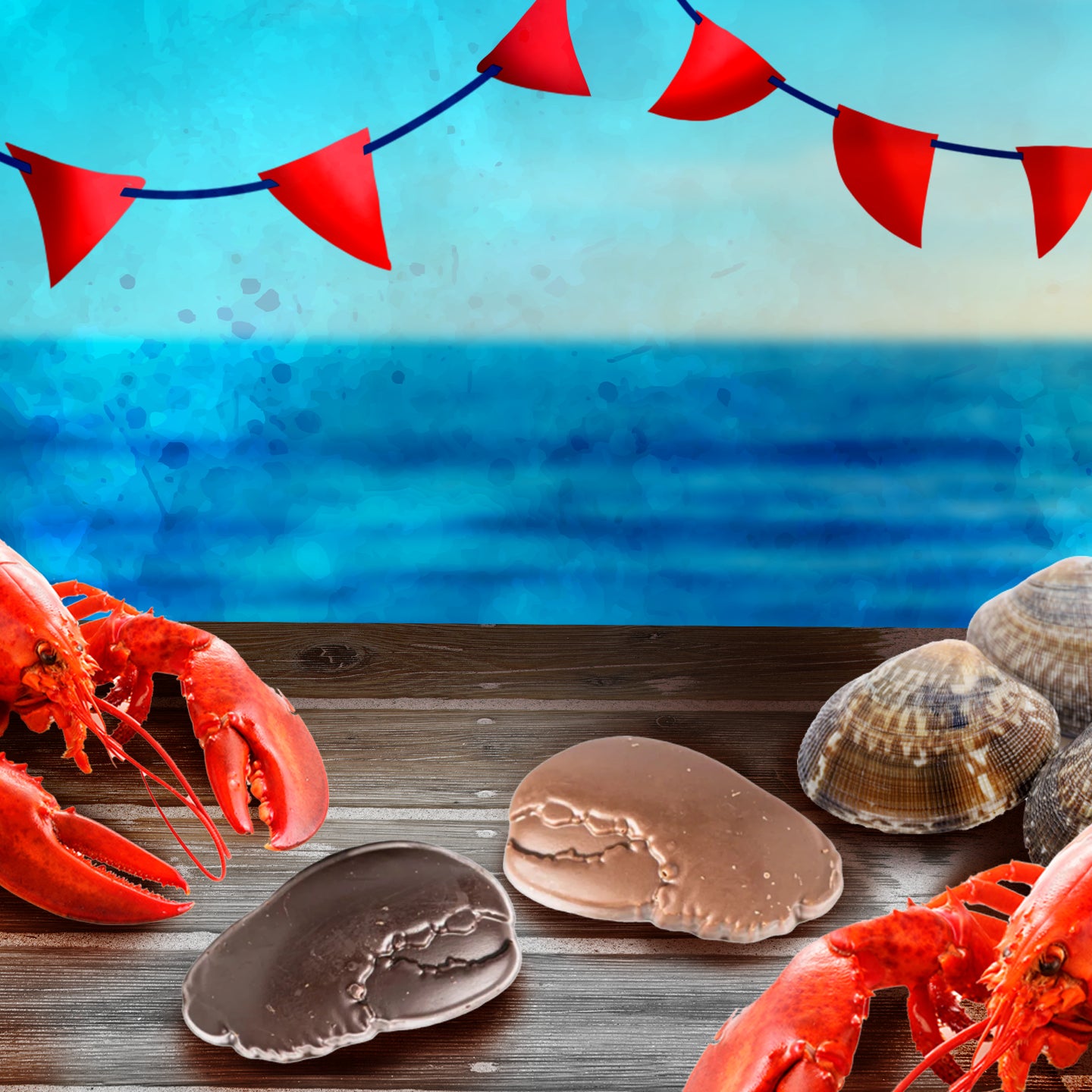 A seaside scene with red bunting, lobsters, clams, and two chocolate sea shell candies on a wooden table, with the blue ocean and sky in the background.