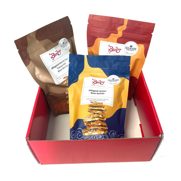 A red box holds three upright, colorful pouches of Bixby Chocolates Beer Brittle Gift Box, an artisanal treat made with Allagash Beer; each pouch has a unique design and clear front label.