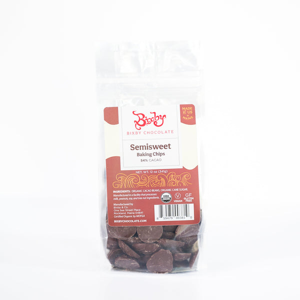 A clear bag of Bixby Chocolates Baking Chocolate Chips (54% cacao) with a red and white label shows bean to bar chips. The packaging highlights that they are organic, vegan, and gluten-free.