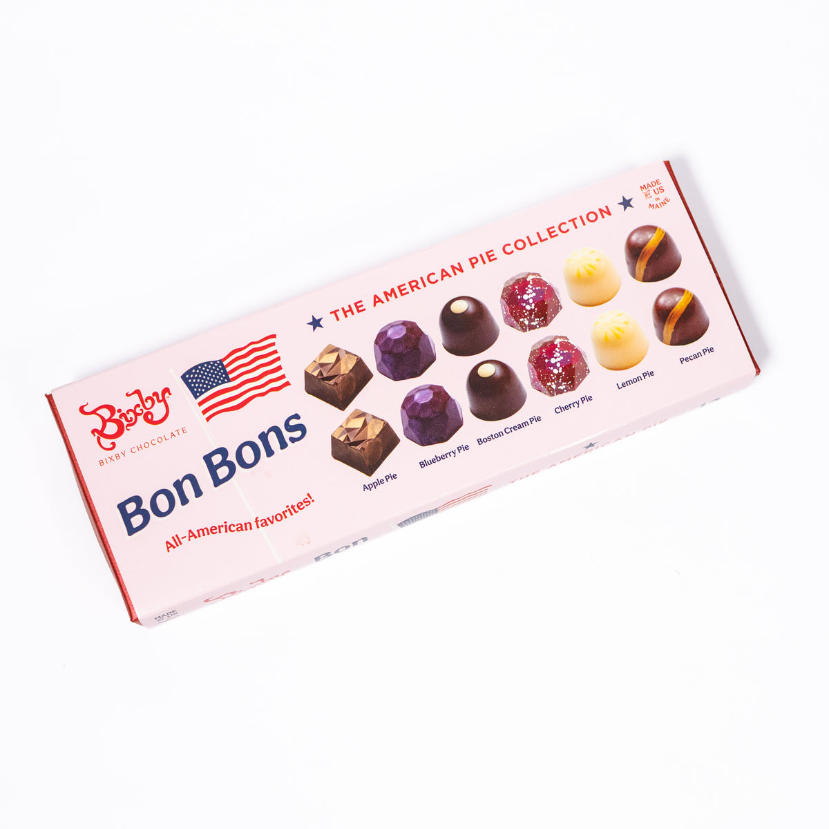 A package of Betty Best Chocolate Bon Bons, 'The American Pie Collection', shown at an angle on a clean white background. The box is light pink with red and blue text and features illustrations of various chocolate bonbons with pie and lemon toppings.